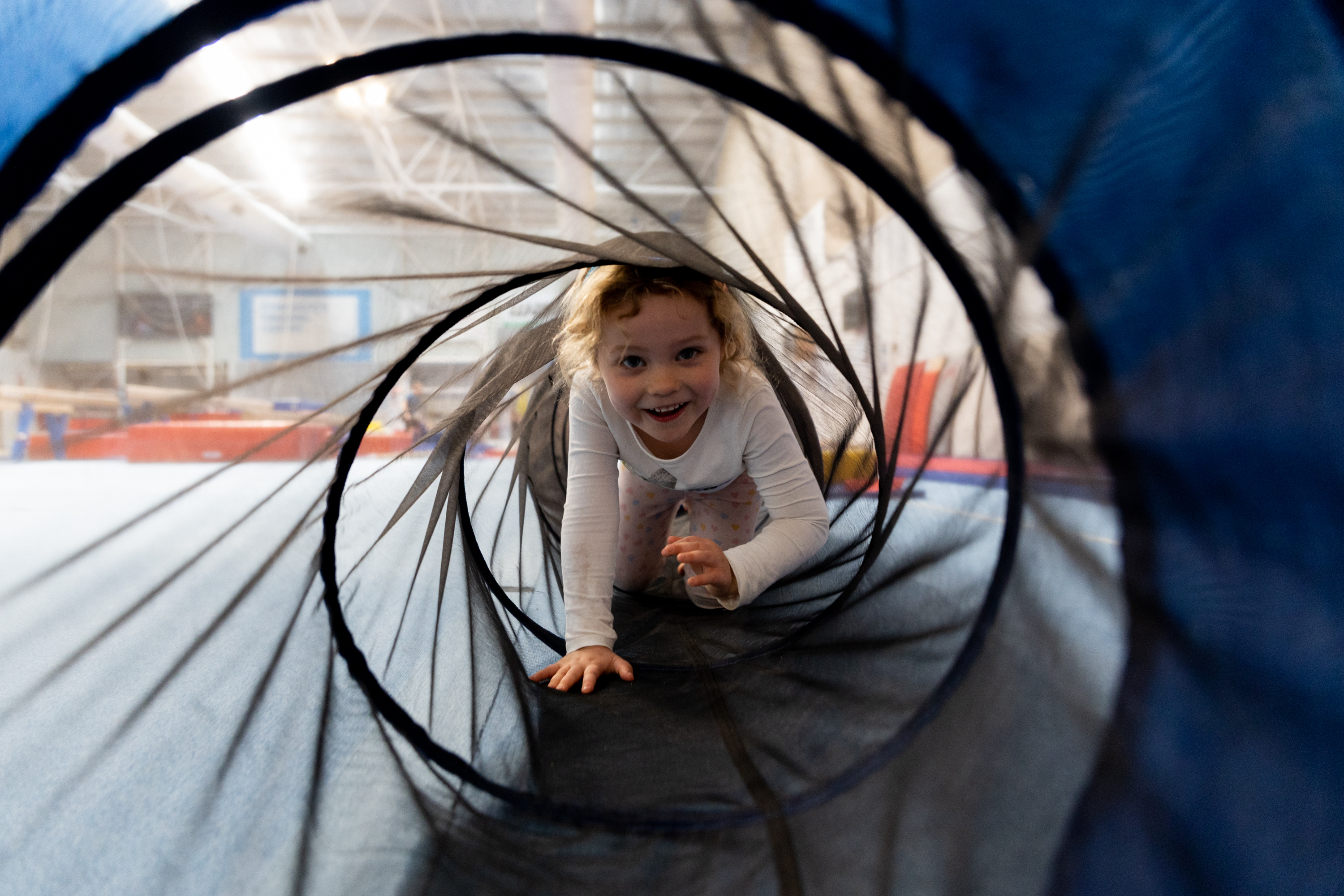 Young girl climbing through play tunnel at kindy gym